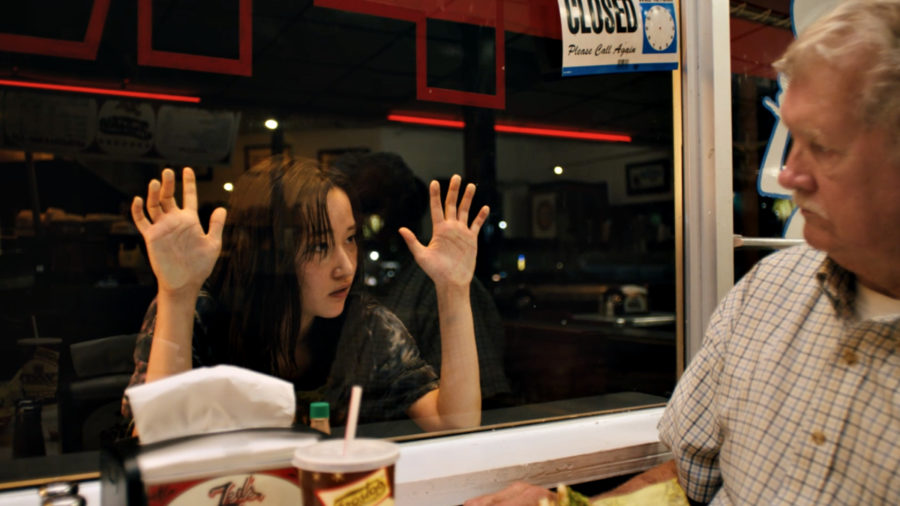 Jeon Jong-seo como Mona Lisa mirando a un señor a través de una ventana de un restaurante 